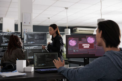 Rear view of woman using laptop at office