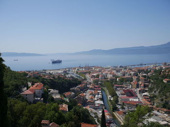 High angle view of townscape by sea against clear sky