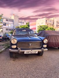 Vintage car on street in city against sky