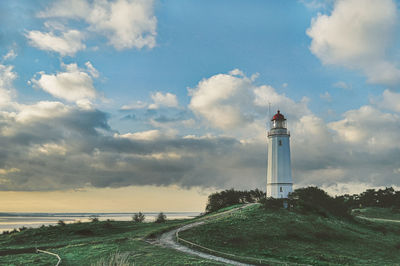 Lighthouse by sea against sky