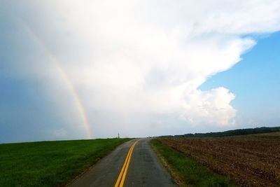 Rainbow over road against sky