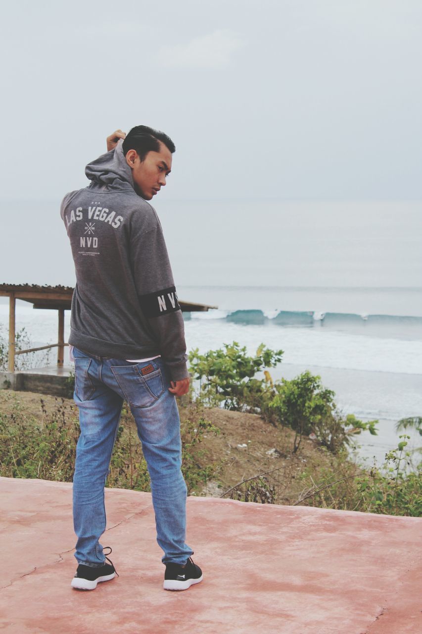 FULL LENGTH OF YOUNG MAN LOOKING AT SEA