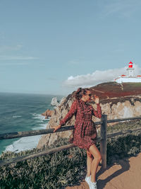 Woman standing by sea against sky