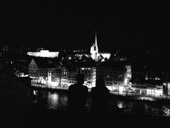 Rear view of people looking at city at night