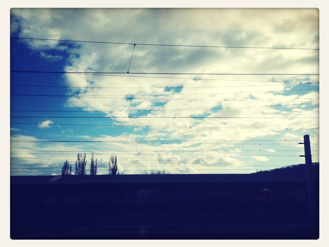 sky, cloud - sky, silhouette, low angle view, power line, transfer print, cloudy, cloud, built structure, auto post production filter, architecture, cable, connection, sunset, power supply, electricity pylon, dusk, electricity, building exterior, weather