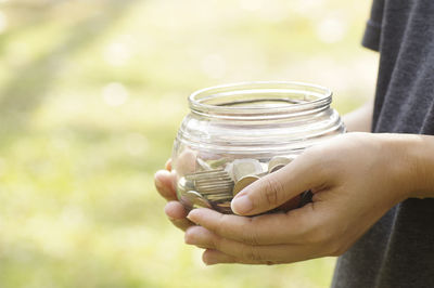 Close-up of hand holding jar with coins