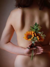 Naked woman holding flowering plant