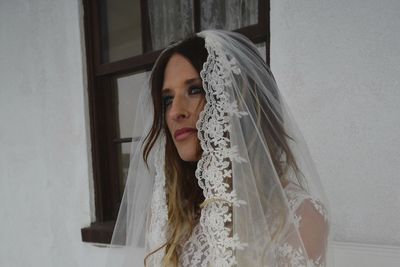 Thoughtful bride standing by window