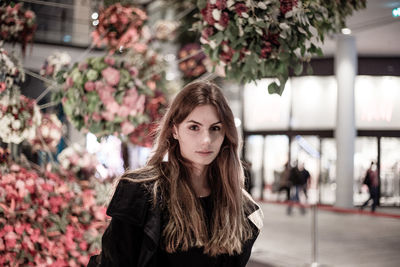 Portrait of young woman with long hair by flowers