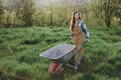 Young woman with wheelbarrow on grassland