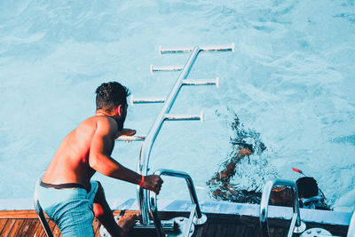 Rear view of shirtless man in swimming pool