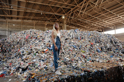Portrait of young woman standing against garbage heap