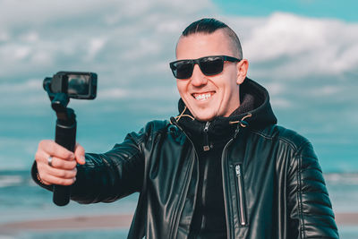 Young man blogging while standing at beach