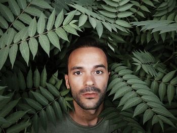 Portrait of young man with leaves outdoors