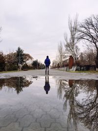 Rear view of man walking on puddle