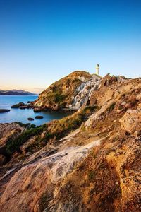 Lighthouse by sea against clear sky