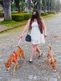 Full length of young woman with dog walking in park