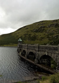 Bridge over river against cloudy sky