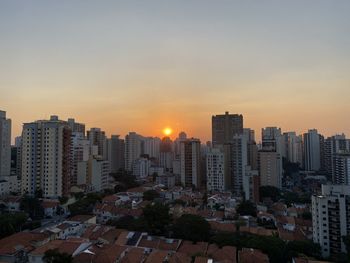 Modern buildings in city against sky during sunset