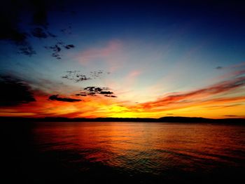 Scenic view of sea against dramatic sky during sunset