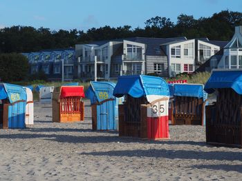 Multi colored umbrellas on beach by buildings against sky