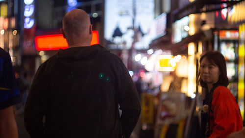 Rear view of people standing on street in city at night