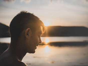 Close-up portrait of man at beach against sky during sunset