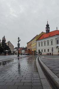 Wet street amidst buildings in city during rainy season