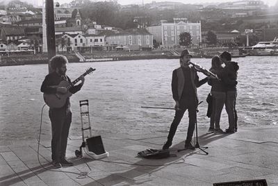 Rear view of men playing guitar in city