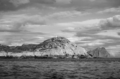 Scenic view of a rugged hill crowned by a small white lighthouse. ideal for coastal showcases. 