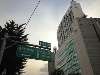 Low angle view of road sign by building against sky