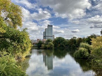 Scenic view of river by trees and buildings against sky