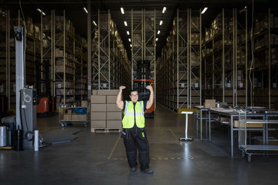 Full length of mature female warehouse worker gesturing while standing at storage room