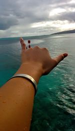 Close-up of hand against sea