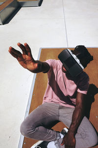 High angle view of teenager gesturing while using virtual reality on road during sunny day