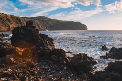 Rock formation on beach against sky