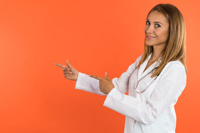 Portrait of young woman with arms crossed against yellow background