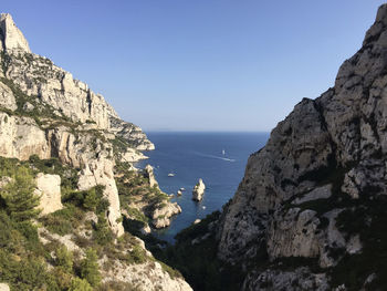 Scenic view of sea and mountains against clear blue sky