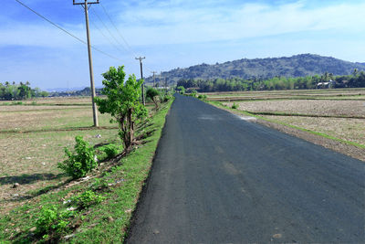 Road amidst green landscape against sky