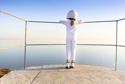 Rear view of girl standing by railing at observation point against clear sky