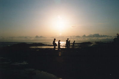 Silhouette people walking on calm beach