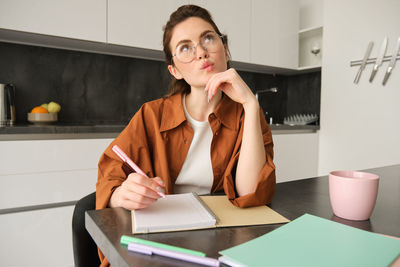 Portrait of young woman using mobile phone while sitting at home