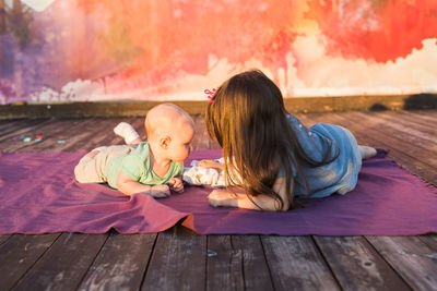 Rear view of mother and girl sitting on wood