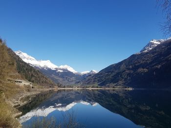 Scenic view of lake and mountains against clear blue sky