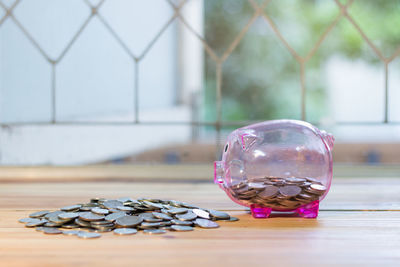 Close-up of piggy bank and coins on table