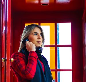 Low angle view of woman talking on telephone while standing in booth