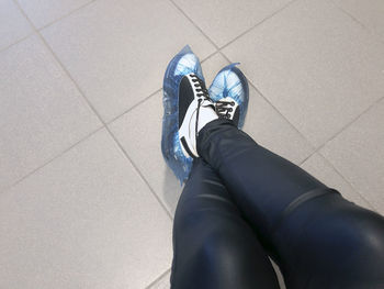 Low section of person wearing shoes on tiled floor