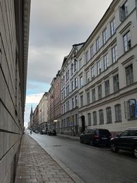 Cars on street amidst buildings in city against sky