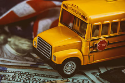 Close-up of figurine school bus on paper currency