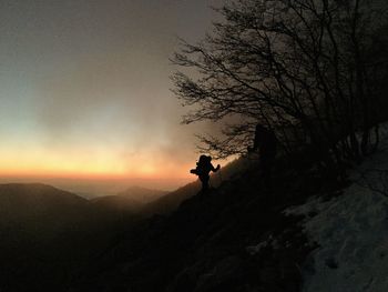 Silhouette people standing on mountain against sky during sunset